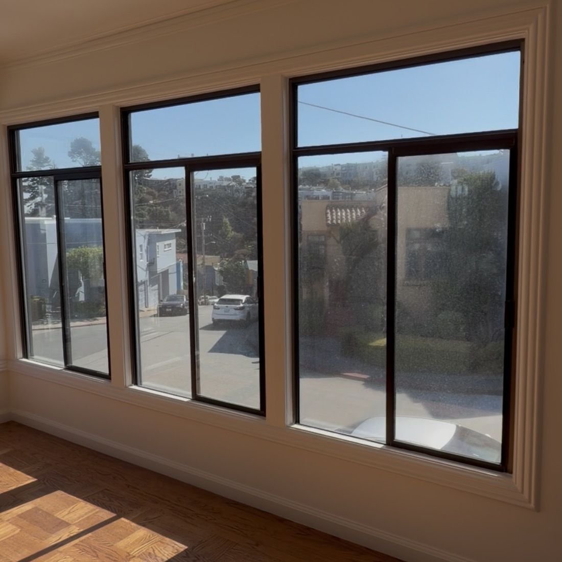 Sunroom windows before cleaning, the right-hand window speckled with spots that blur the view of the street
