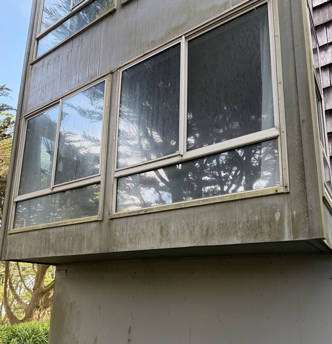 Before cleaning: streaky glass and mildew-stained siding on the outside of a home