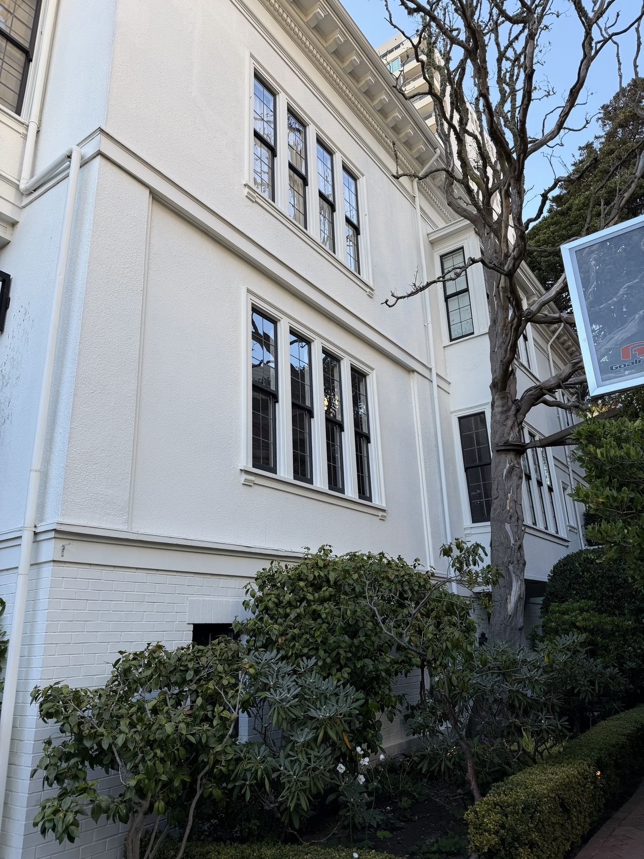 Rows of freshly cleaned divided-light windows on a white stucco wall