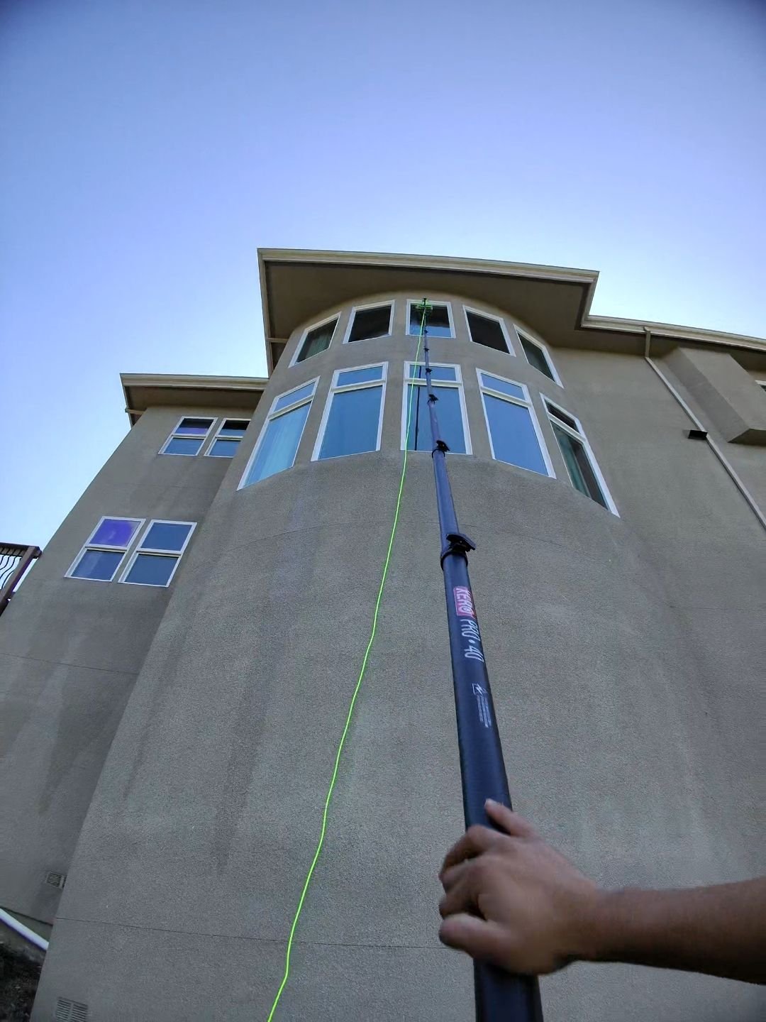 A water-fed pole reaching the top row of windows on a curved stucco tower