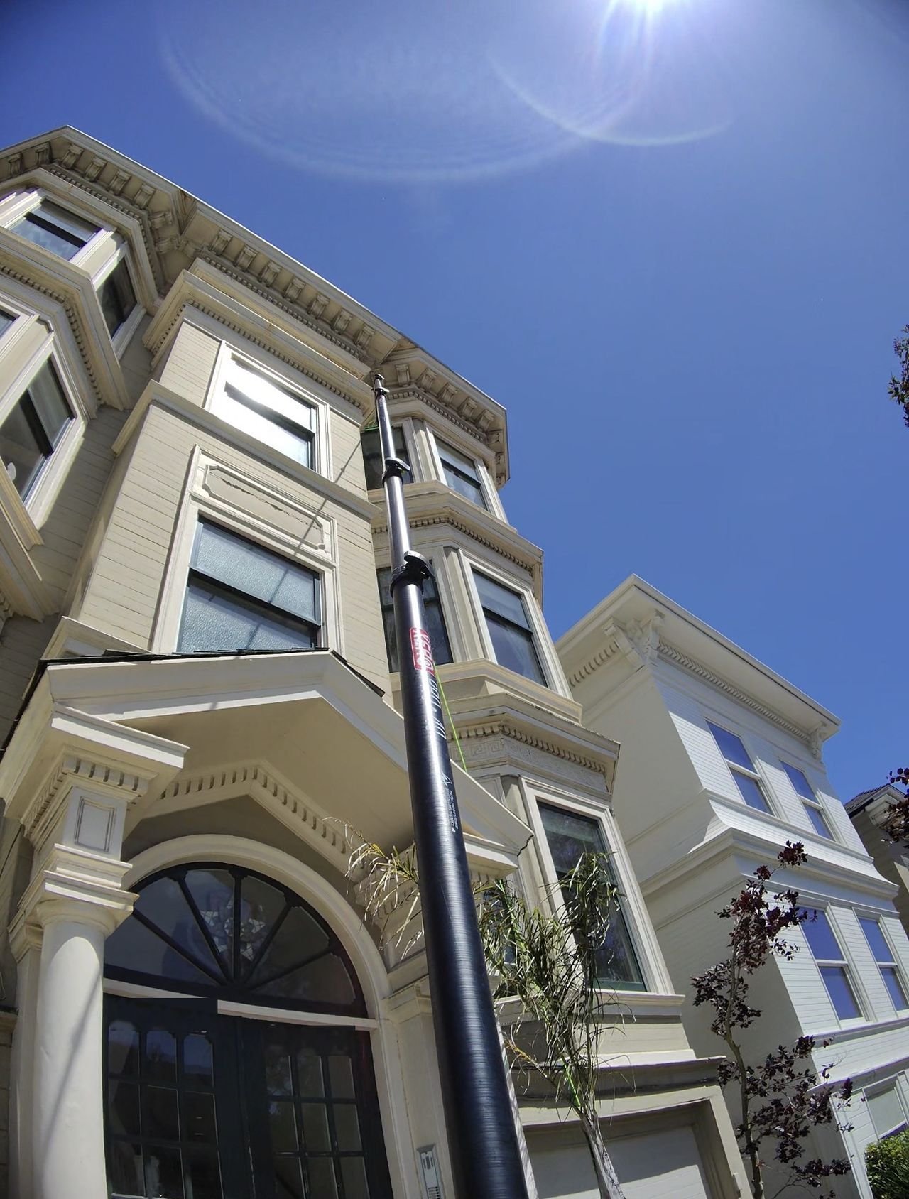 A Crystalviews water-fed pole rising past four stories of bay windows on a San Francisco Victorian