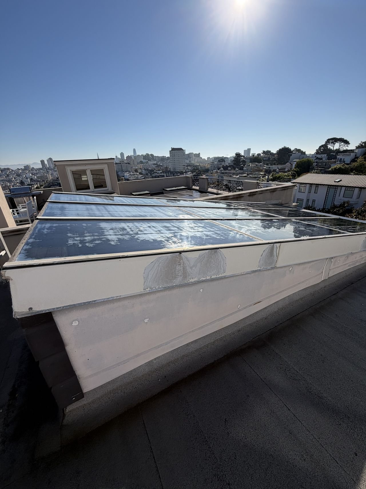 Before cleaning: a rooftop skylight with chalky buildup, with the San Francisco skyline behind