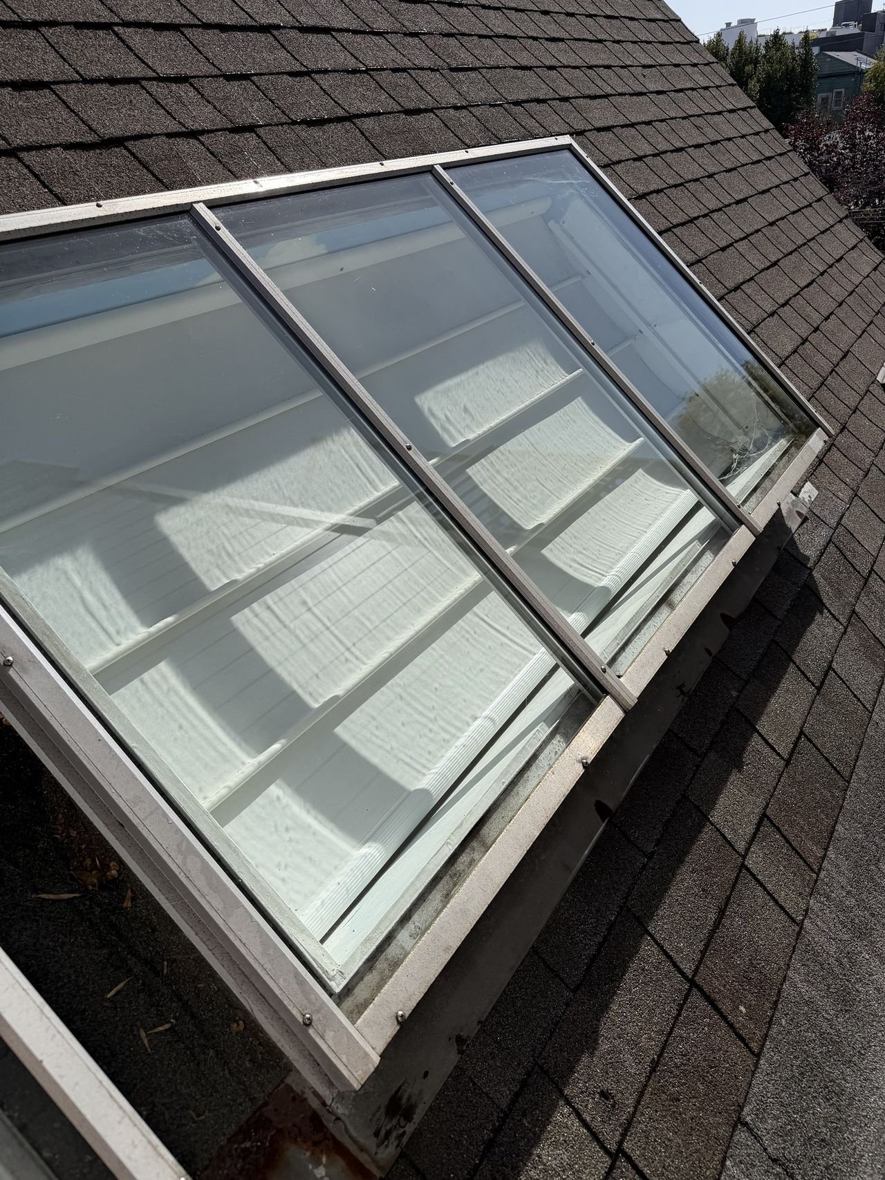 A row of large skylights on a shingled roof