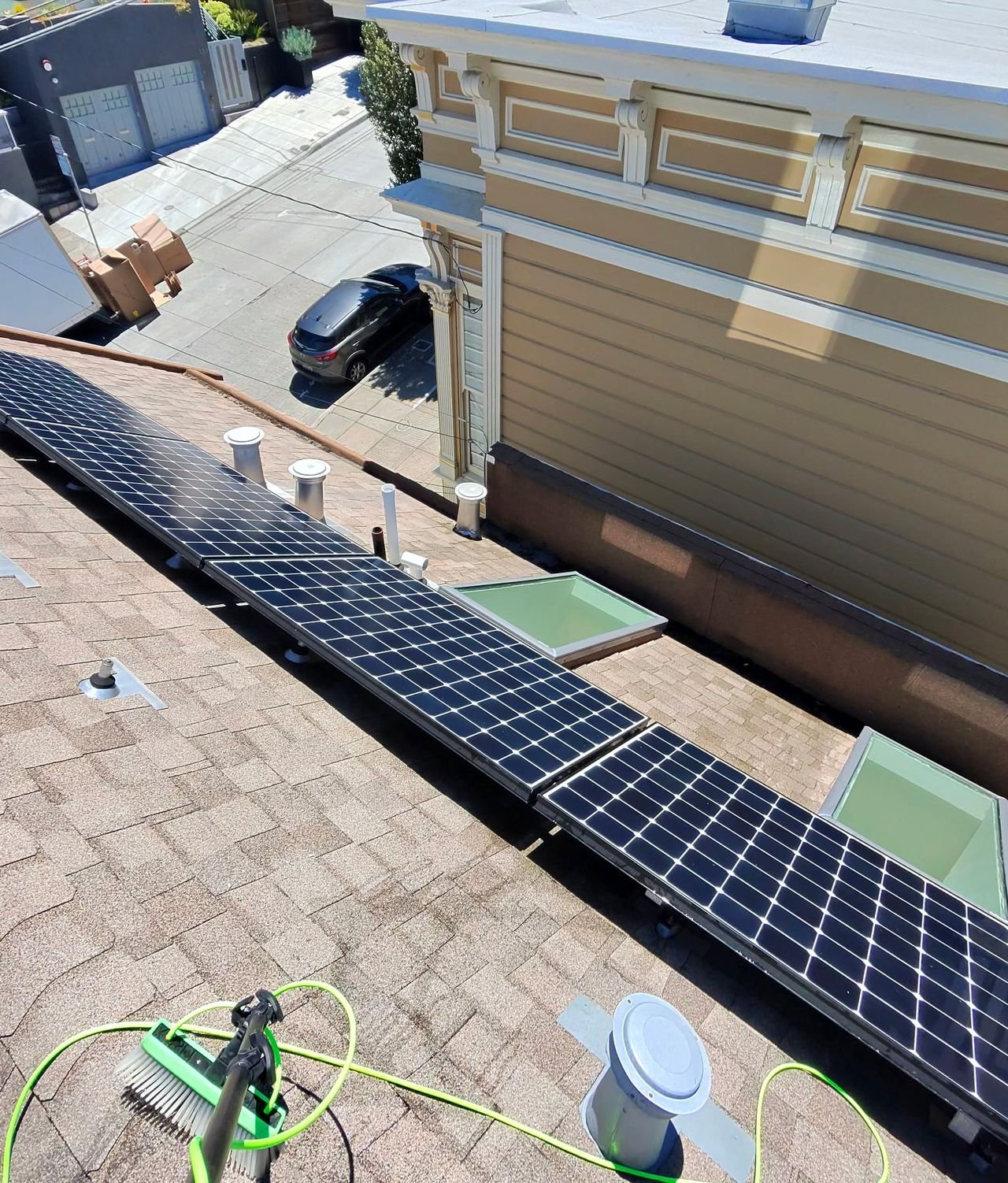 A soft brush on a water-fed pole beside a row of solar panels on a San Francisco roof