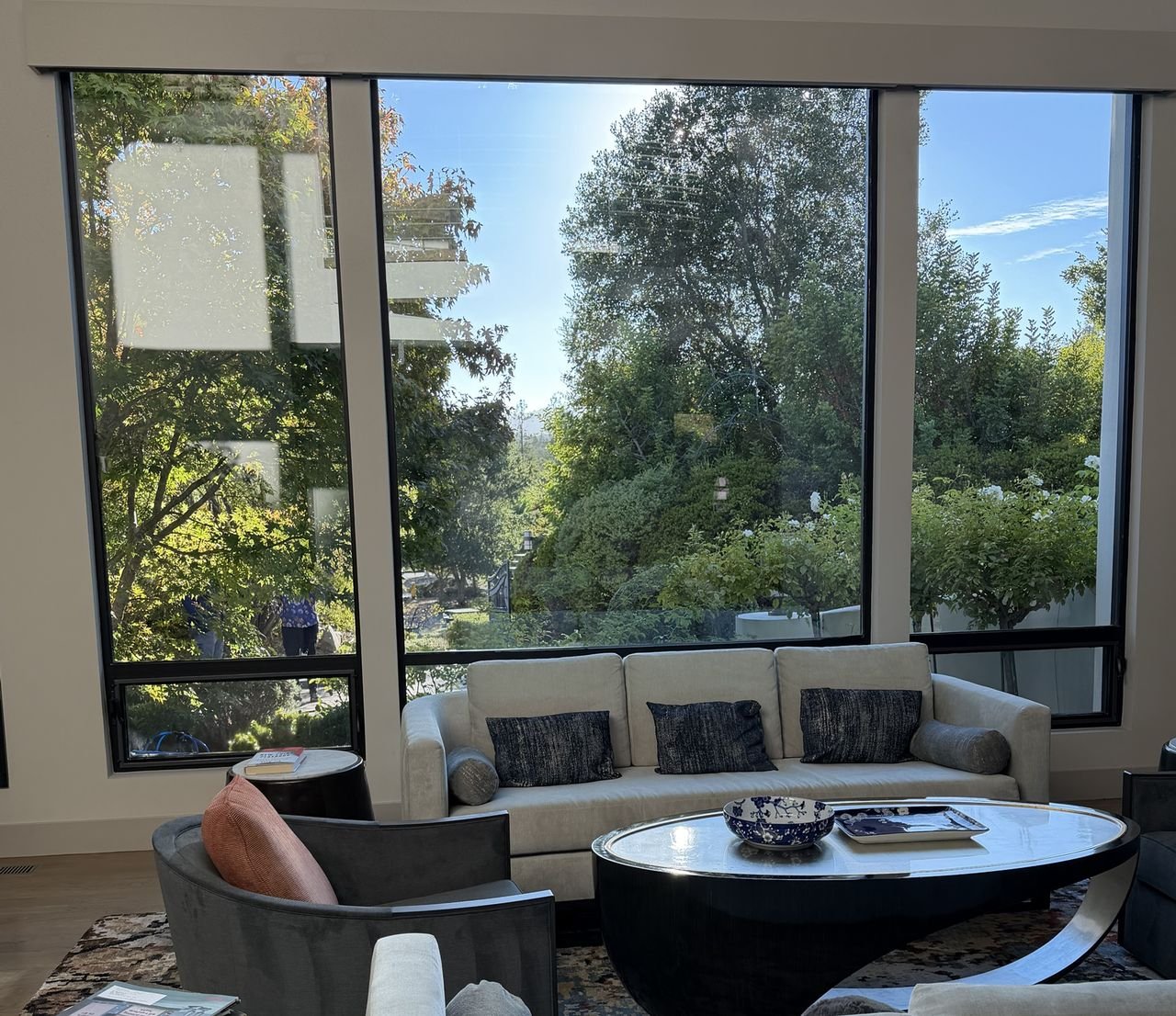 A living room with tall, freshly cleaned windows looking out on trees